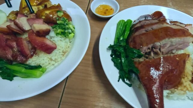 Overhead view of authentic traditional Cantonese dish featuring roast goose leg (Si Yip) roasted chicken (Siu Gai) and crispy pork belly (Siu Yuk) at a local restaurant in Hong Kong