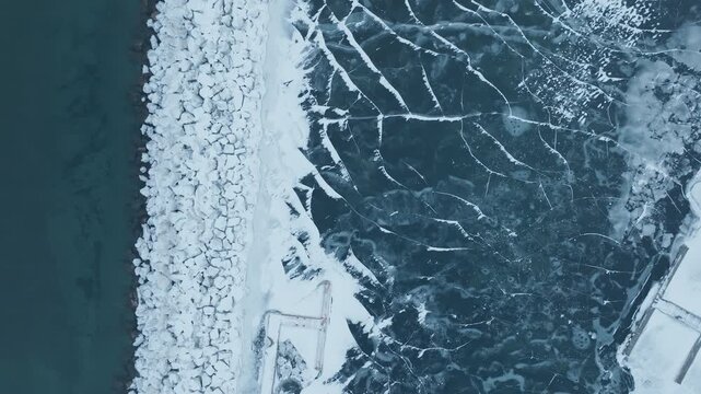 Aerial view of icy Bronte Harbour meeting Lake Ontario's cold waters