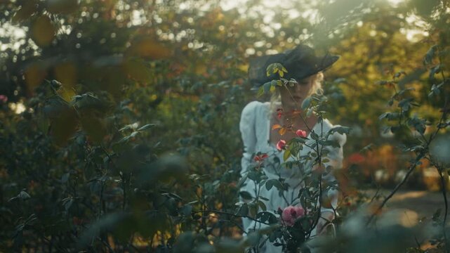 Lady Tending Vibrant Roses In Garden. Graceful Woman Caring For Blooming Roses Under Gentle Sunlight