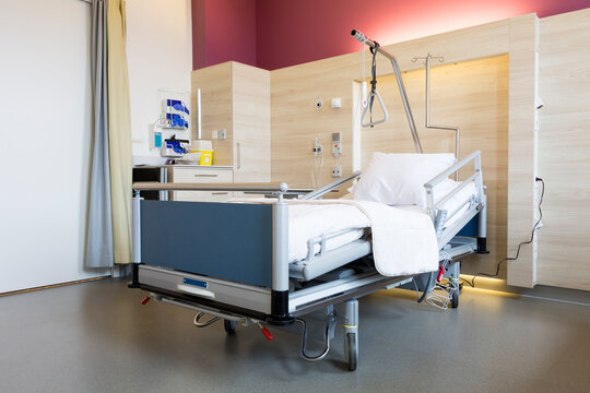 A hospital room in a Dutch hospital shows a patient bed with surrounding medical equipment. The room has a simple design and bright lighting. Walls are clean with soft colors.