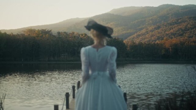 Woman By Water. Tranquil Scene Showing Woman In Gown Overlooking Water During Sunset With Cinematic Tone