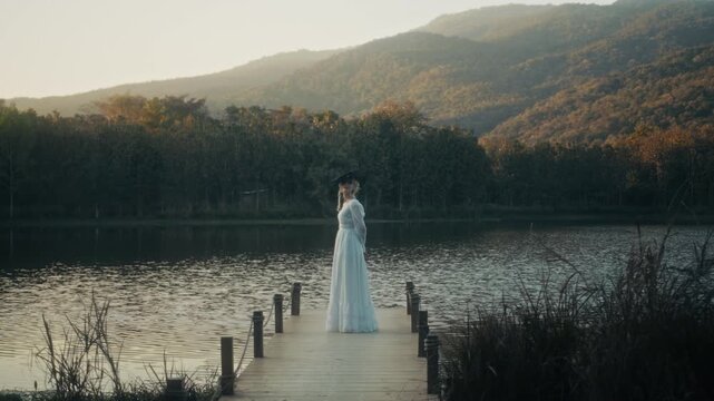 Woman By Water. Tranquil Scene Showing Woman In Gown Overlooking Water During Sunset With Cinematic Tone