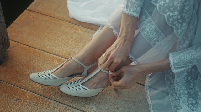 Intimate Moment Of Bride Fixing Her Sandal. Warm Sunrise Illuminates Bride Adjusting Footwear On Dock