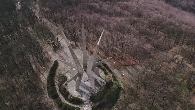 Aerial drone footage of the Kosmaj Monument in Serbia, capturing its brutalist concrete structure against the sky. Memorial site from above.
