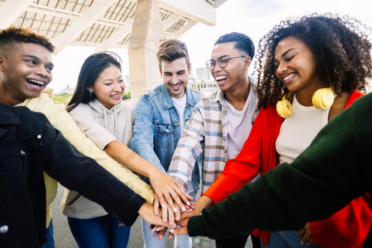 Group of cheerful gen z students standing together, holding hands as a sign of support and togetherness. Youth lifestyle concept.