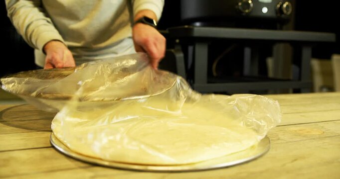 Cook putting fresh pizza dough on circular tray - steady cam