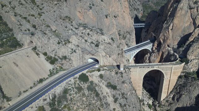 Aerial view of cars driving on mountain road with bridges and tunnels