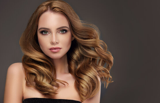 Brown hair  girl with long  and   shiny wavy  hair .  Beautiful  model woman with curly hairstyle . Beauty and cosmetology .  Hair coloring technique Balayage and Shatush. 