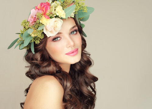 Beautiful woman model brunette with long curly hair floral wreath on the head . Spring. Beautiful woman with clean fresh skin on face . Girl facial  treatment . Cosmetology , beauty  and spa