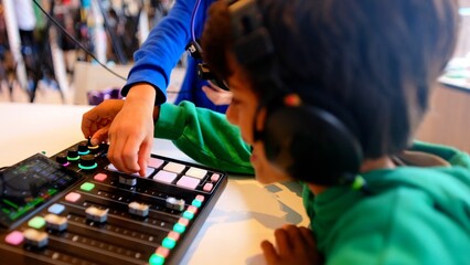Children learning music production, operating a sound mixer with headphones on during a creative workshop, exploring dj skills and digital audio equipment © DawDunia