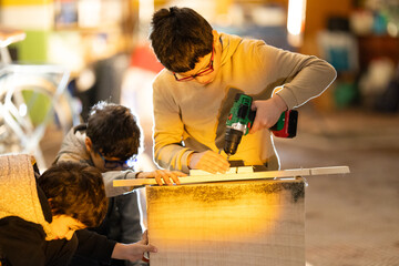 Young boys learning woodworking using a power drill