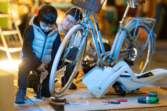 Young boy learning bicycle repair with sibling