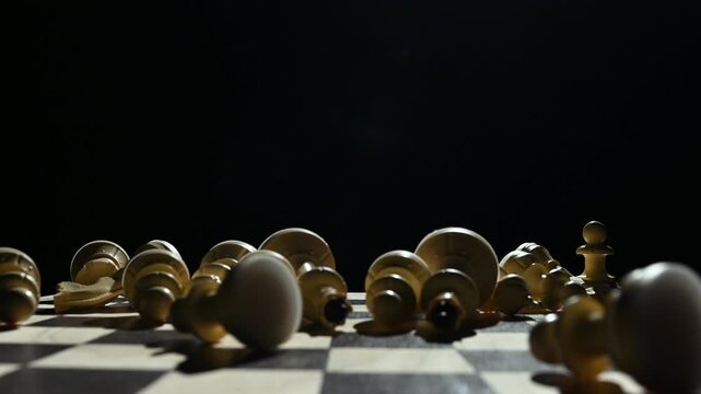 White chess pieces on a black background stand in a row, and the chess player's hand passes over them, knocking them down onto the game board. 4к