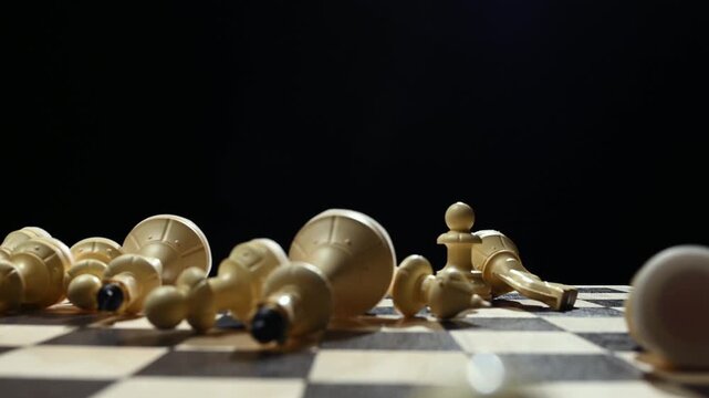 White chess pieces on a black background stand in a row, and the chess player's hand passes over them, knocking them down onto the game board. 4к