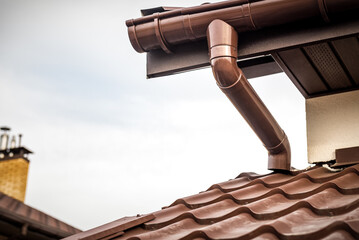 Brown rain gutter and rain water pipe at a roof