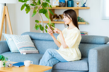 部屋でスマホを操作する女性