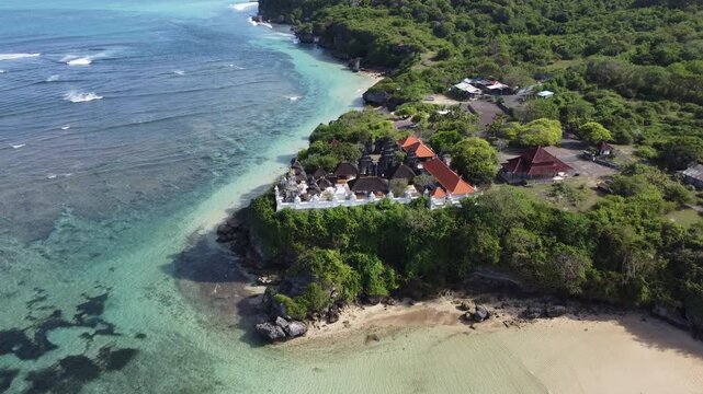 Aerial drone orbiting left around cliffside temple overlooking Geger Beach in Nusa Dua, Bali, Indonesia.
