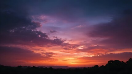 Vibrant sunset with dramatic clouds painting the sky in hues of orange pink and purple over a silhouetted landscape