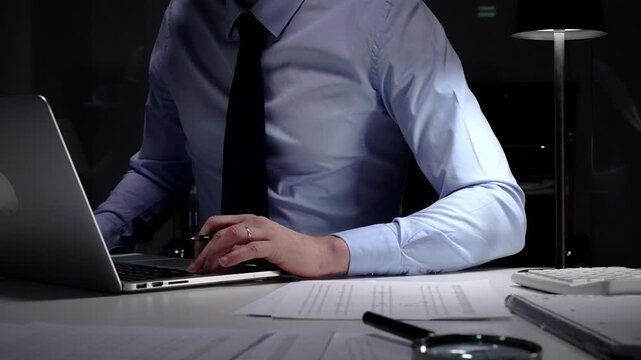 Businessman working late at night, typing on laptop, meeting deadlines and managing corporate finance administration. Audit and taxes in business