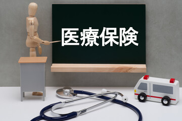 黒板に書かれた医療保険とデッサン人形
