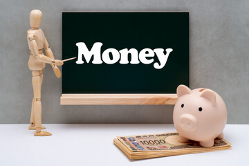 黒板に書かれたMoneyを示すデッサン人形