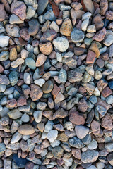 Natural multicolored river pebbles and small stones forming textured gravel background