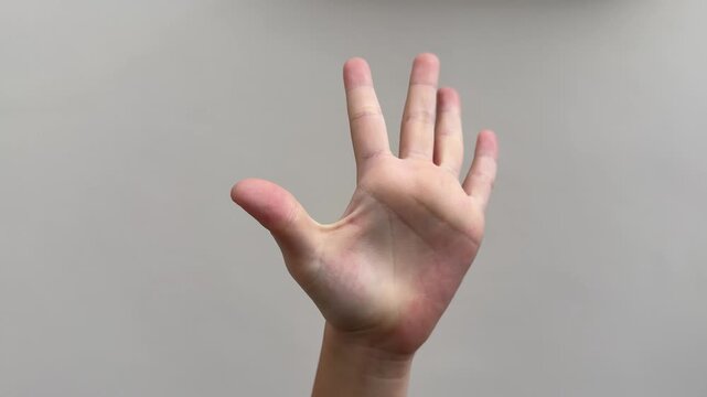 A small hand demonstrates finger counting gestures from one to five and back down to zero, isolated on a clear wall background.