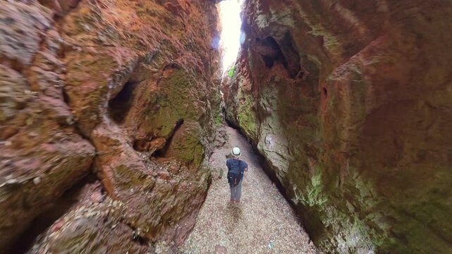 Person hiking and exploring through a deep, narrow canyon of high rock walls in Quebrada del Toro in Lagunas de Ruidera Natural Park exploring the natural landscape. Ossa de Montiel, Albacete