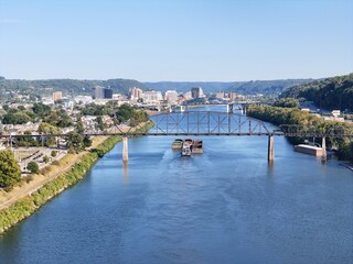 The South Charleston City river scene featuring multiple bridges With Railroad Bridge named the Travis L. Castle Railroad Trestle spanning the wide blue Kanawha River, with green hills in distance.
