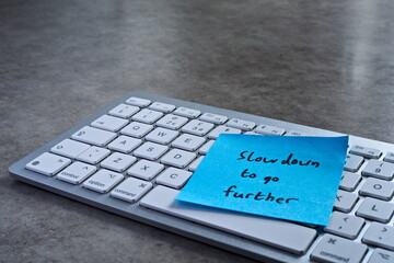 "Slow down to go further" sticky note left on keyboard. The bright note stands out against the keys, symbolising motivation, productivity, and a focused mindset. © Shannon Muranyi