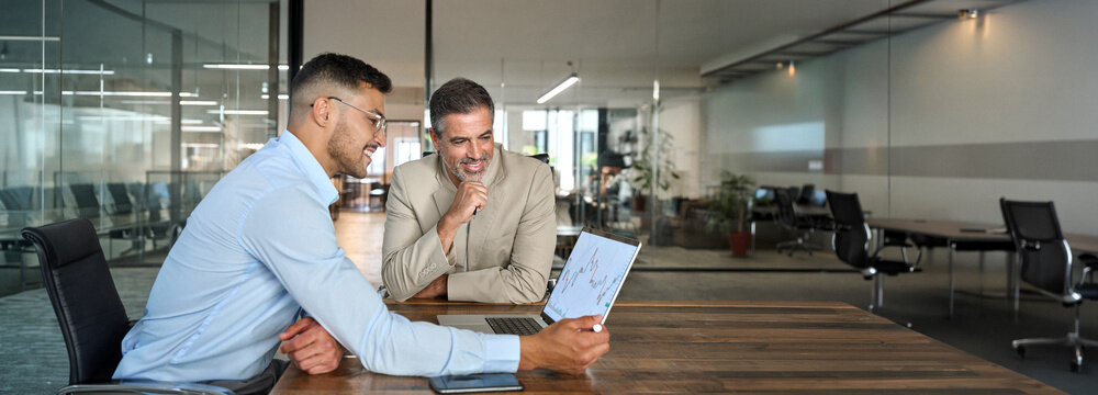 Financial advisor consulting investor explaining financial trade stock data using laptop computer. Professional analyst showing market trends in crypto exchange planning investment at office meeting.