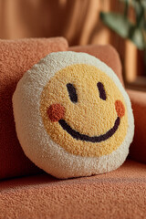 Smiley face pillow sits on a couch in a cozy indoor setting with furniture