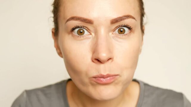 A woman demonstrates a sequence of reactions while tasting food. She explores initial curiosity, surprise, delight, and various expressions of taste and enjoyment. The background is plain and neutral