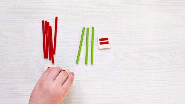 Top view video of child&rsquo;s hands learning to count using colorful wooden counting sticks, arranging math example on table. Educational activity supporting early math skills and cognitive development.