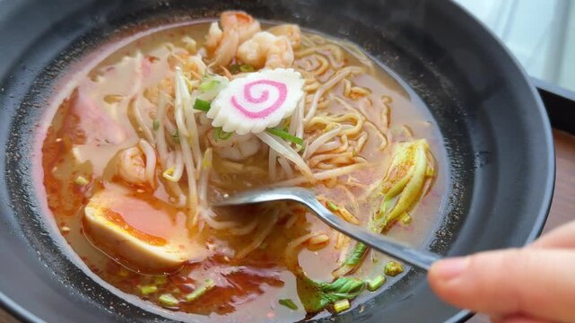 Enjoying a bowl of ramen with seafood and vegetables in a restaurant setting during lunch hours