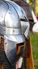 Naklejka premium Polished metal helmets and chainmail hang on display outdoors, detail showing leather lining