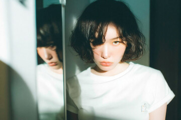 Obraz premium Moody Portrait of Young Asian Woman with Mirror Reflection