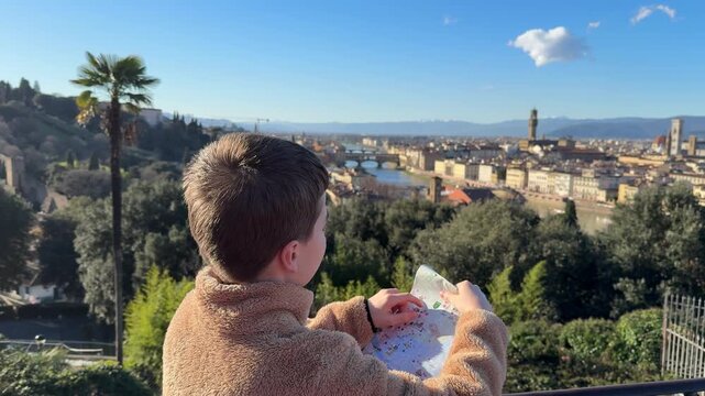 Child holds map while looking over Florence, Italy on a sunny day with hills in the background