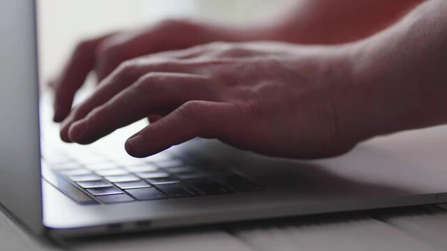 Freelancer working on laptop at wooden table in cafe, close-up of hands.