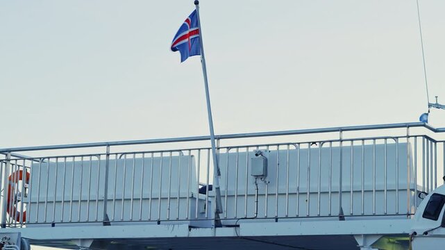 National flag of Iceland waving on the back of a boat at sea during sunrise.