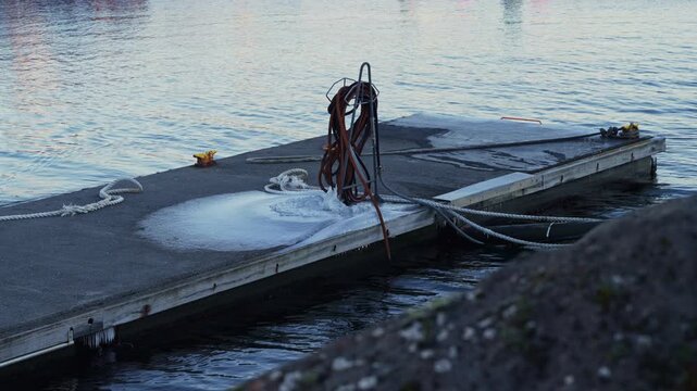 Close up of ice layer on a harbor walkway caused by a water hose in freezing winter weather.