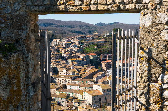 View of Tolfa rooftops through stone window and iron gate