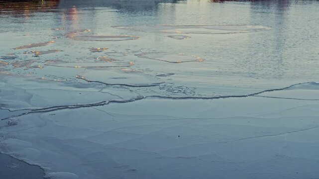 Reflection of boat shadows on frozen sea water with golden sunrise light.