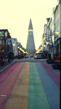Vertical telephoto shot of a colorful street leading to a church at sunrise with shallow depth of field.