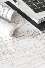 Architectural blueprints with rolled plans and solar panel, sustainable architecture and green building design, renewable energy integration, construction planning background.