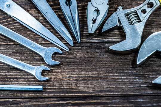 High-resolution image of a complete set of household construction and repair tools arranged on a wooden background. Includes pliers, bolts, hammer, scissors, electrical tape and essential hand tools.