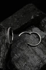 Silver diamond earrings on natural black charcoal background
