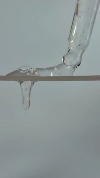 Beauty serum liquid dripped from above by a serum pipette, forming liquid bubbles