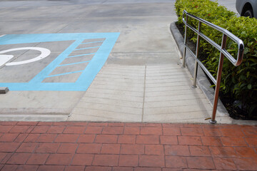 the Wheelchair ramp with nobody in the residence with a garden view. A parking lot with a handicap parking sign and a blue parking space. A metal railing is next to the parking space.