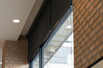 A window with a black blinds and a brick wall behind it